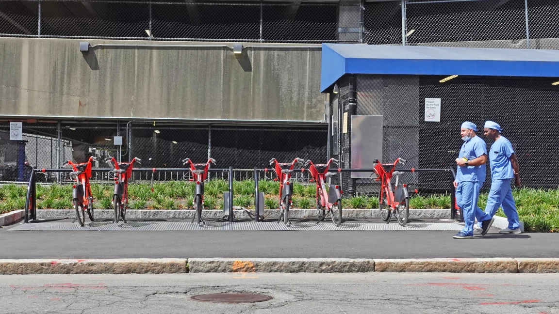 Massachusetts General Hospital staff walking past a Metro Mobility ChargeLock e-bike station